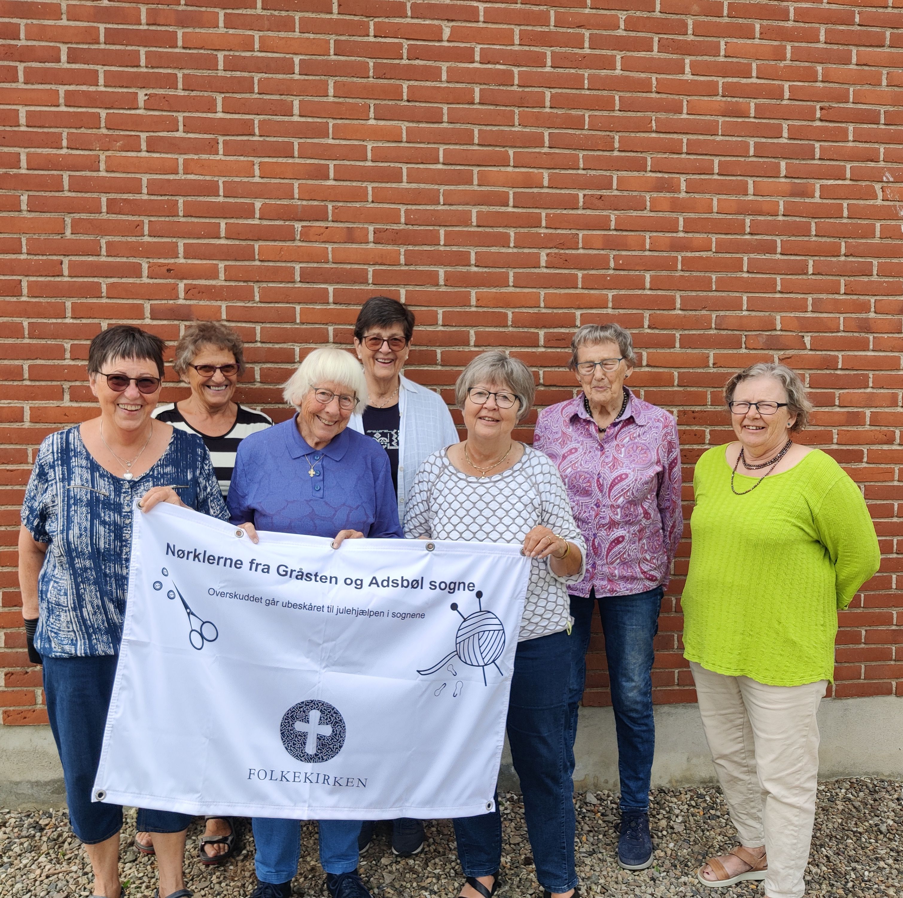 7 damer som holder en banner