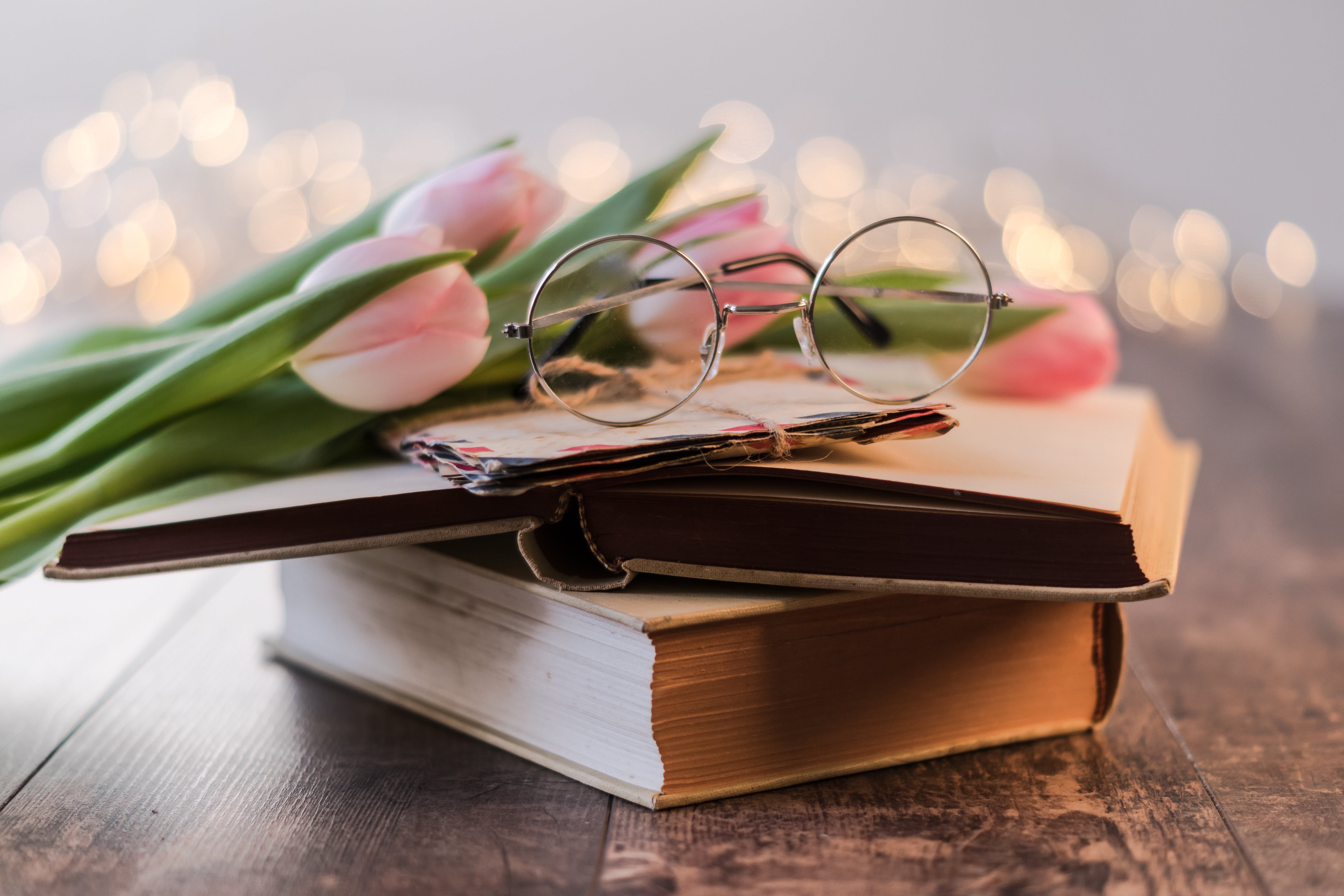 To bøger med et par briller og tulipaner ovenpå